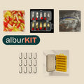 Kit Novato Río de albur: piezas del kit sobre fondo arena; algunas se muestran con imagen ilustrativa (Larvas de silicona 2 cm, 50 uds; Cucharillas ondulantes oro y plata, set de 10 con caja; Minnow hundido 52 mm 4,5 g; Anzuelos baitholder, 200 uds n.º 4; Caja de señuelos de doble cara).